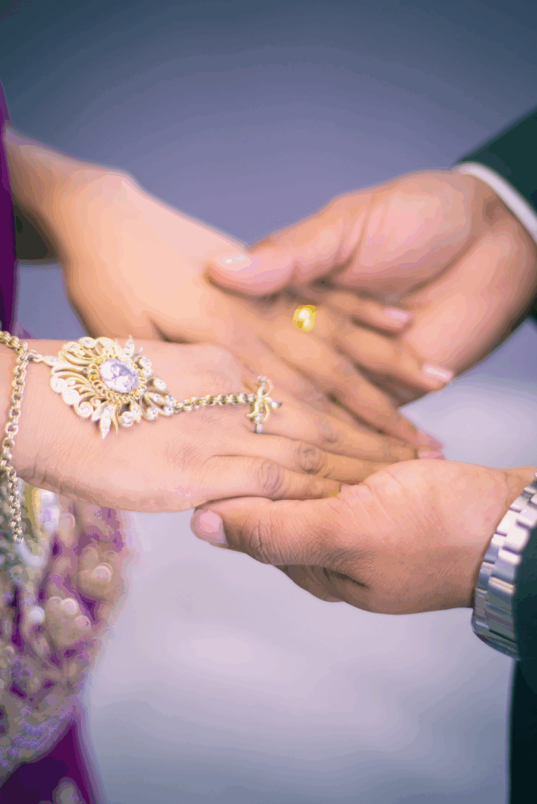 Close up of Indian Woman's bands holding grooms hands
