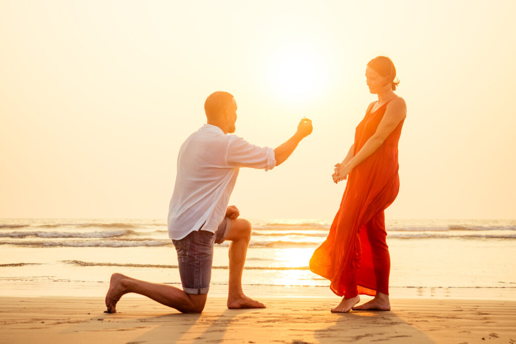 male making proposal with engagement ring to his girlfriend at beach