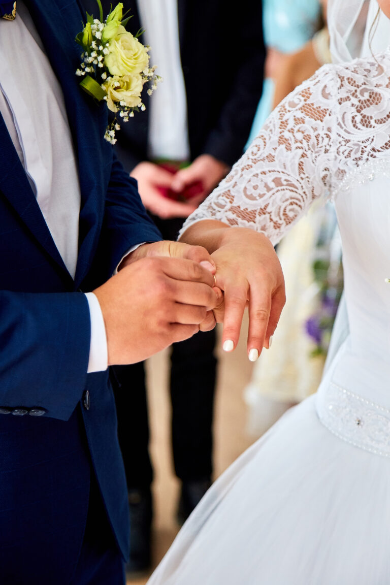 Close up of groom putting ring on brides finger